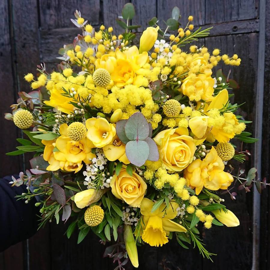 Bouquet de fleurs mélangées composé de jonquille, rose, mimosa, freesia... de printemps dans un camaïeu de coloris jaune.